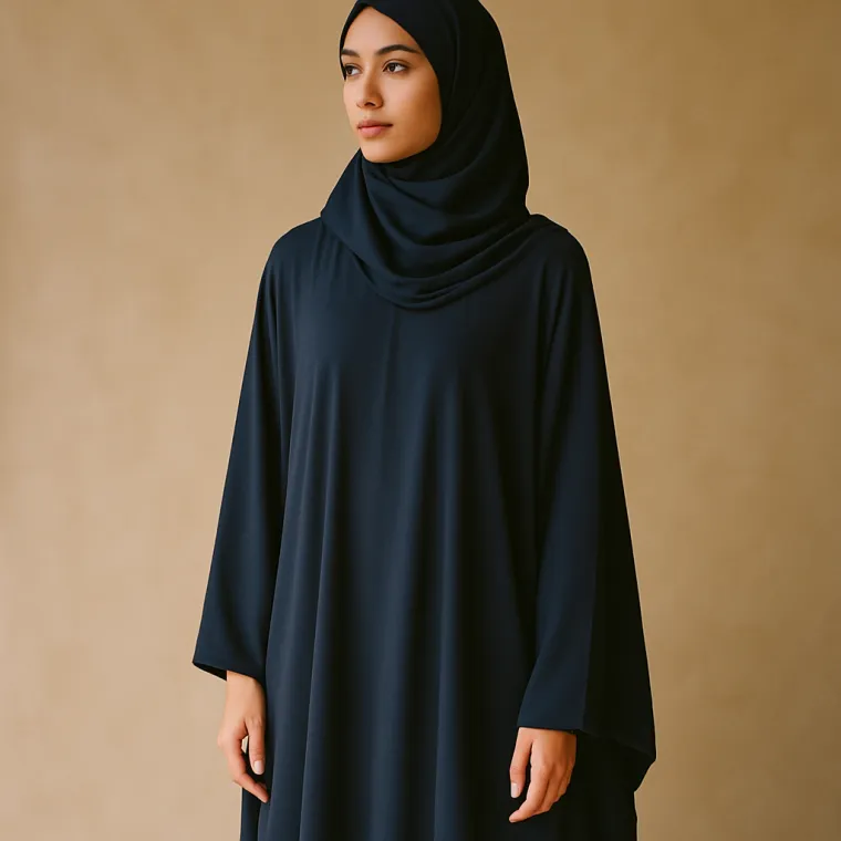 A model wearing a deep navy hijab and a long, softly draped abaya.