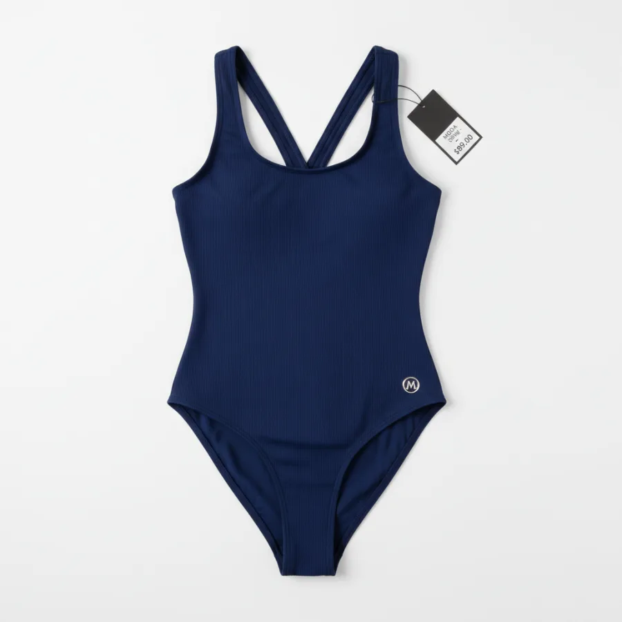 Flat-lay of a navy swimsuit photographed on a plain ground.